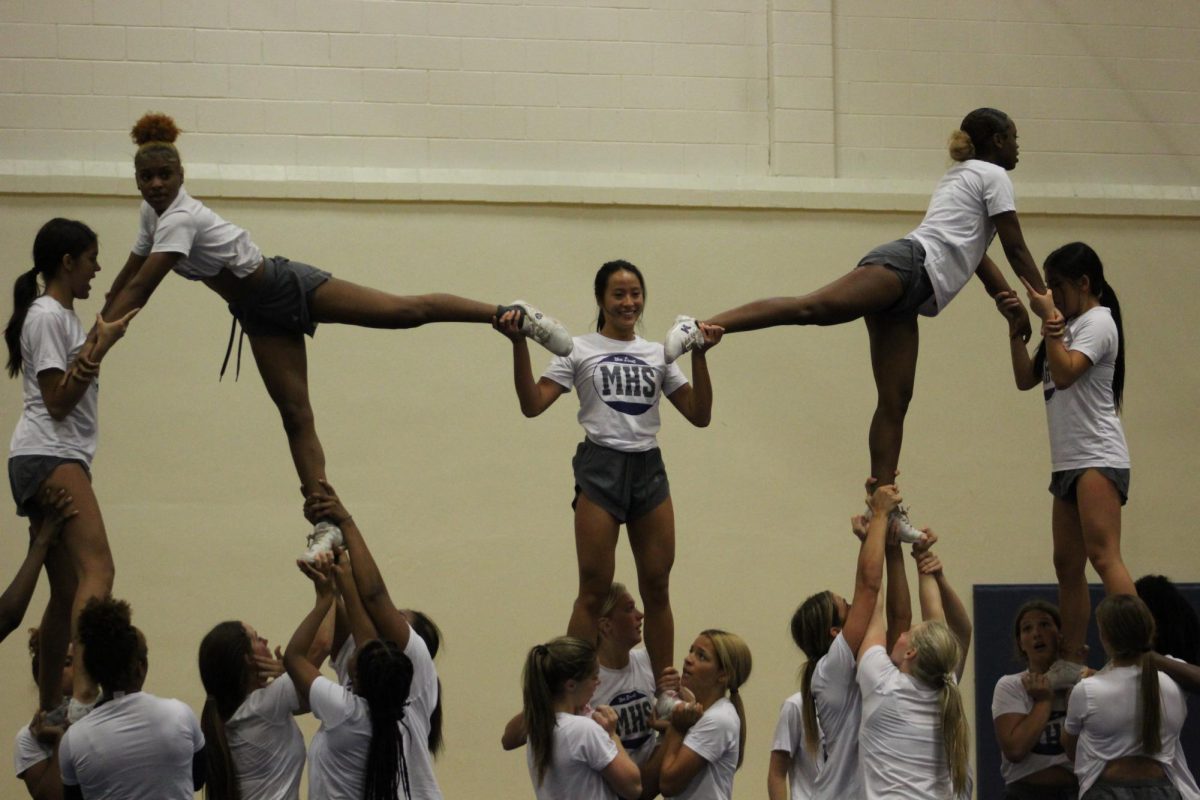 Toffy Siriveerawan (12) performs as middle flyer in a pyramid stunt.