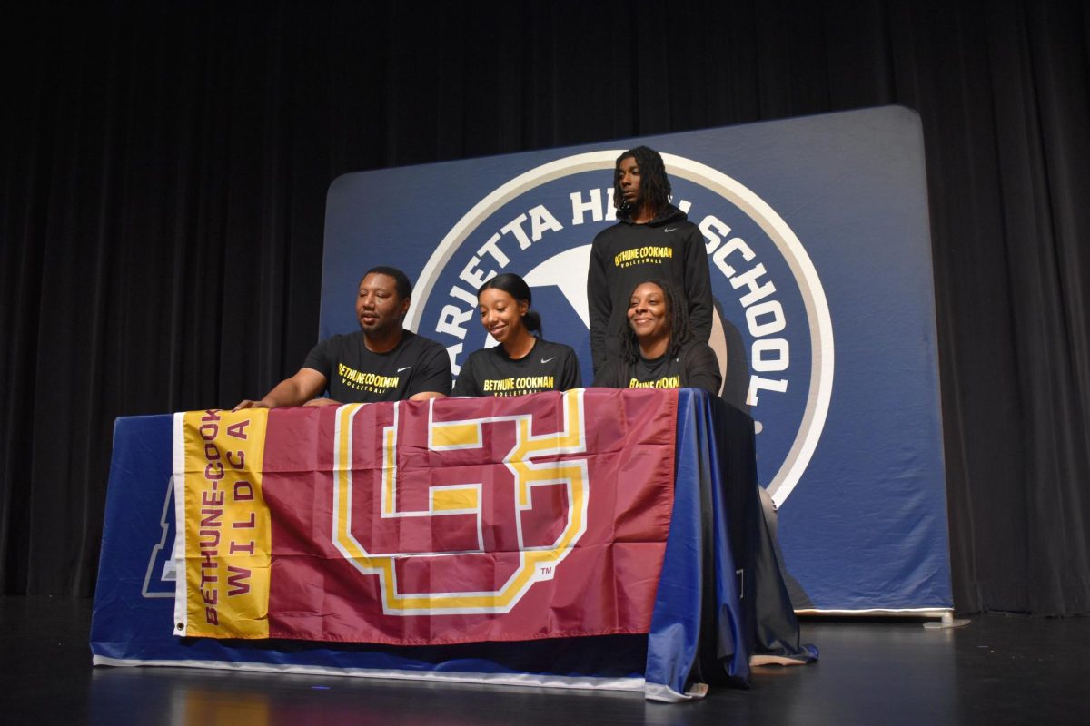 Morgan Wingo (12) signs her commitment to Bethune Cookman University, accompanied by her family. She will play volleyball at the school. 
