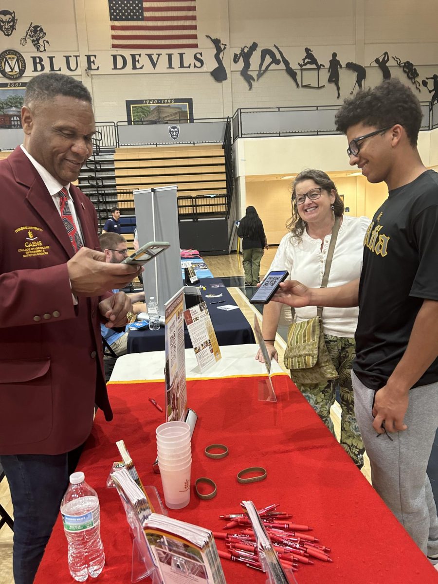 A student from Marietta High and his mom conversing with a college recruiter from Tuskegee University.