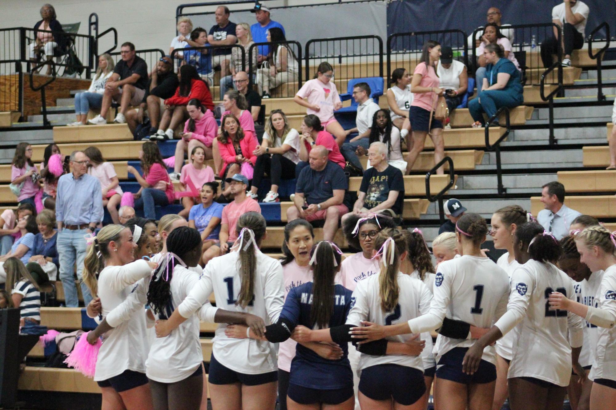 Coach Walker, the new volleyball coach, huddles up with the team.