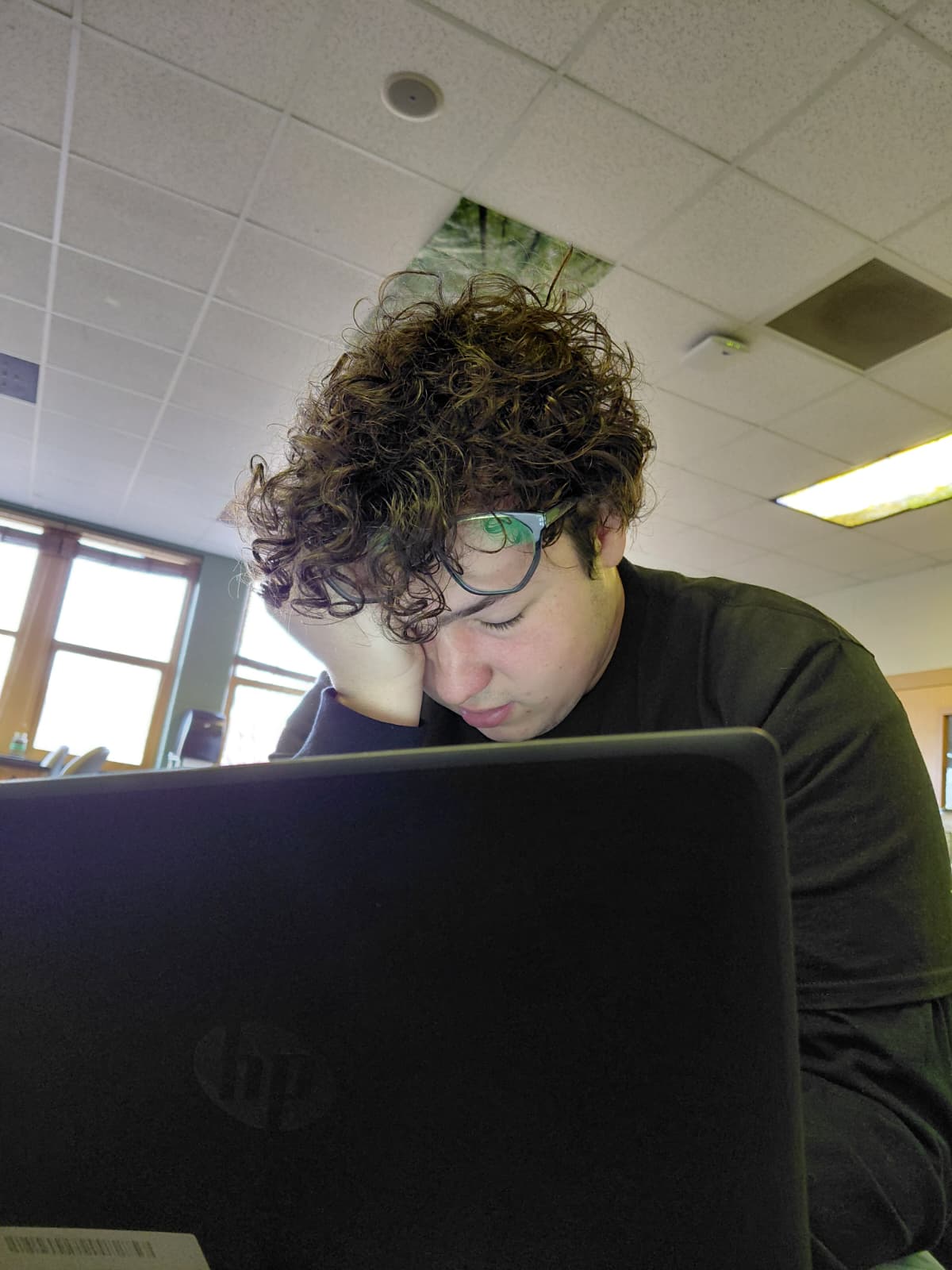 Cristian Lozano rubs his eyes while staring at a device.