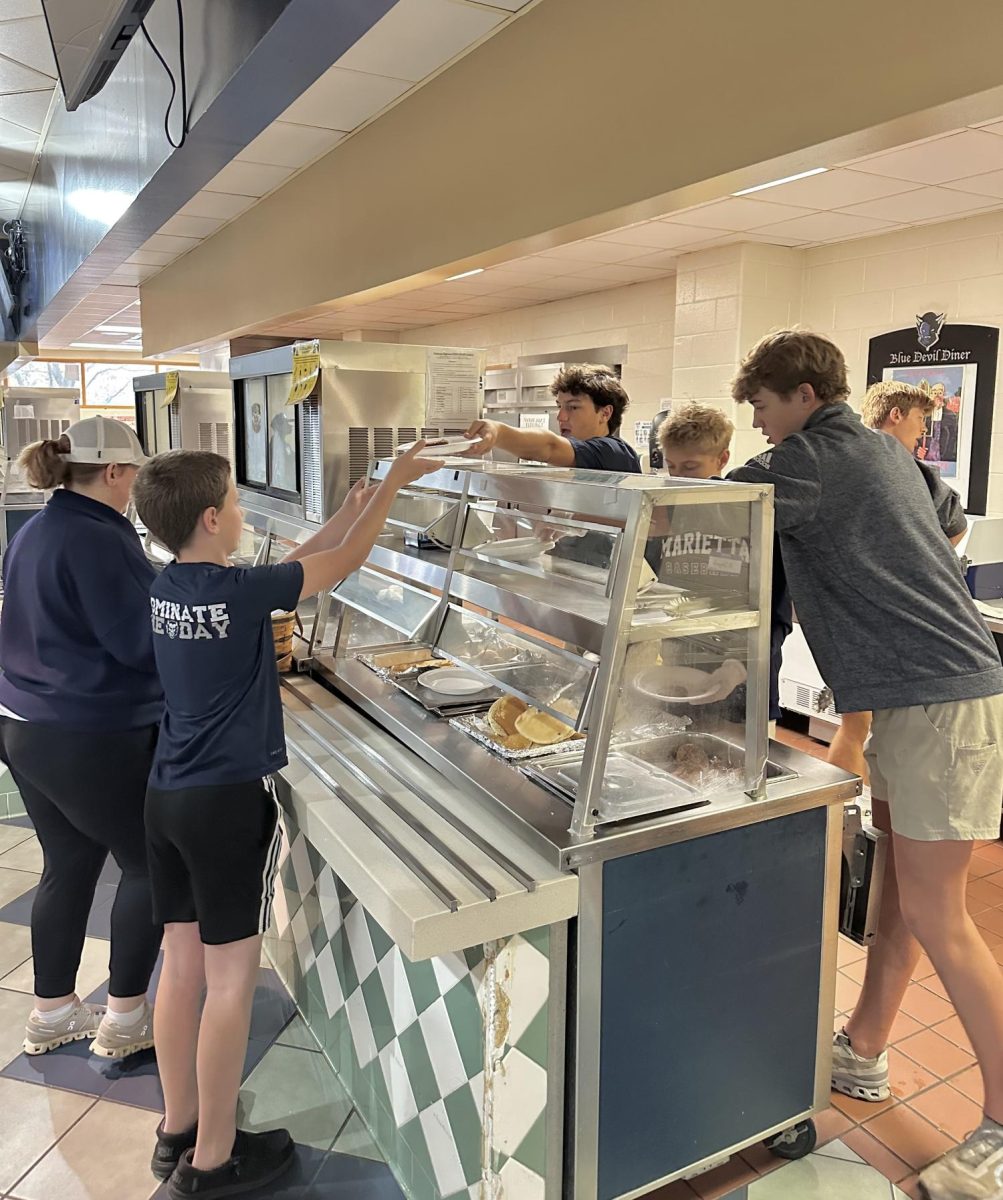 Sophomores serve pancakes and sausage  from the Blue Devil Diner area of the cafeteria. Then customers could grab coffee or juice of their choice to complete their meal.